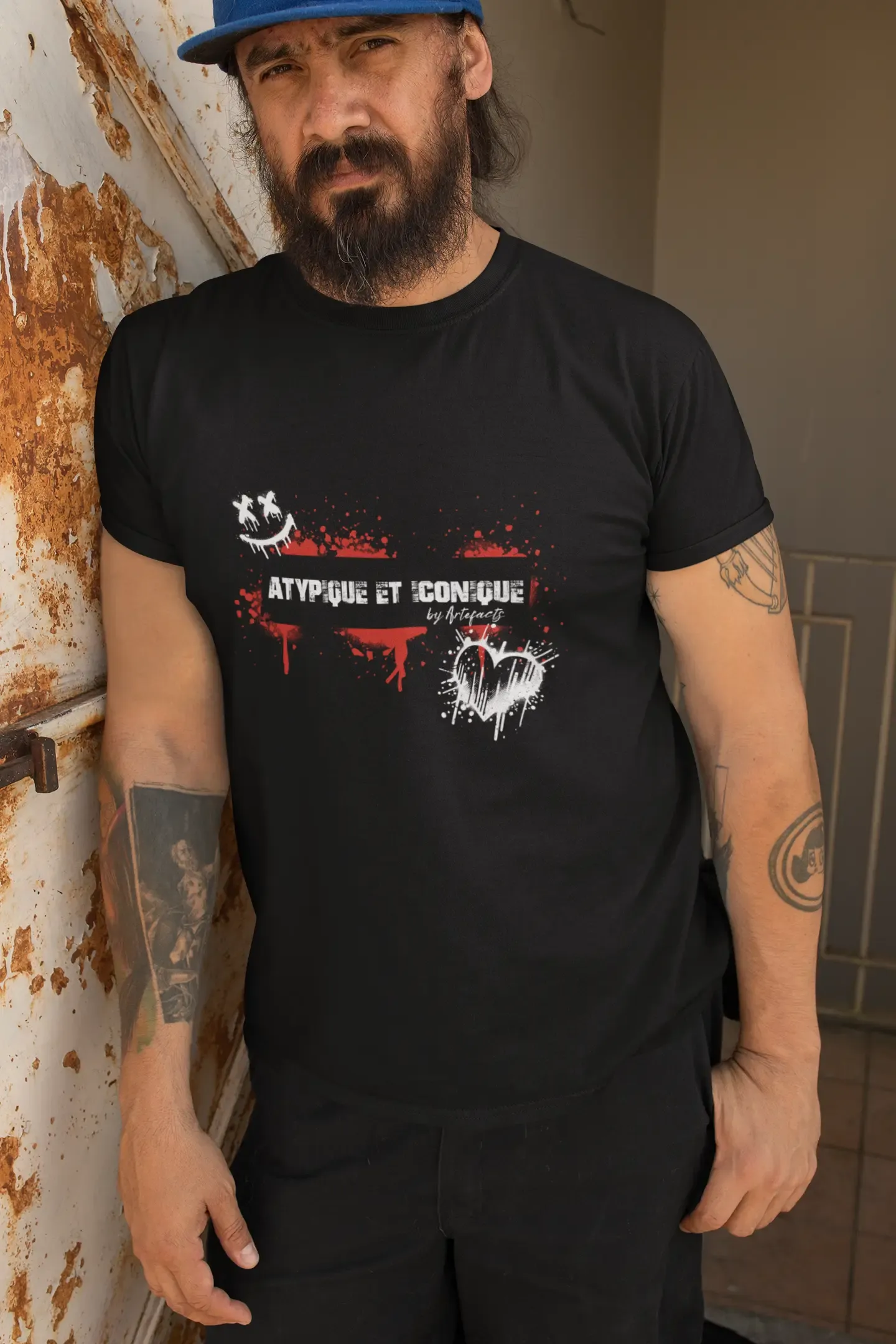 Homme barbu portant un t-shirt noir Artefacts avec l’inscription "Atypique et Iconique" et un design streetwear artistique.